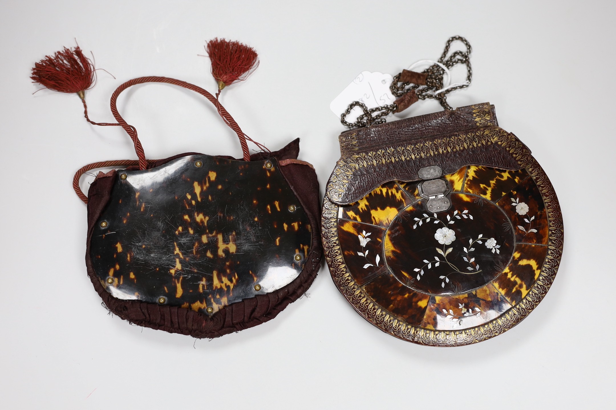 A 19th century circular tooled leather, tortoiseshell and mother of pearl mounted lady’s handbag having a cut steel clasp and chain handle and another similar bag(2)